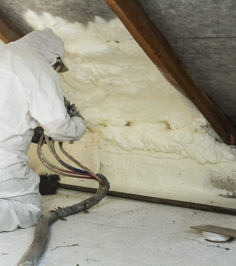 spray polyurethane foam for roof - technician spraying foam insulation using plural component gun for polyurethane foam, inside