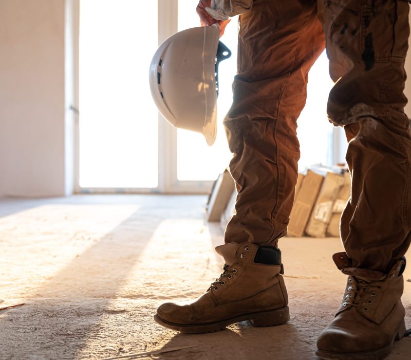 A man builder in work clothes at a construction site, copy space.